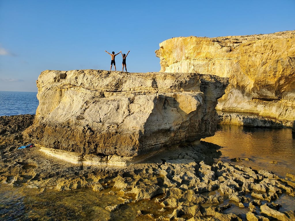 person standing on rock formation near body of water during daytime